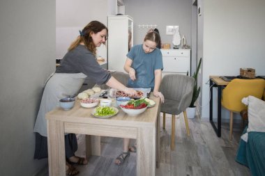 Aile bir arada. Kızı, annesiyle mutfakta pizza pişiriyor. Annesiyle birlikte mutfakta pizza pişiriyor.