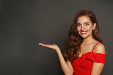 Avuç içi boş gülümseyen kadın siyah arka planda kameraya bakıyor. 