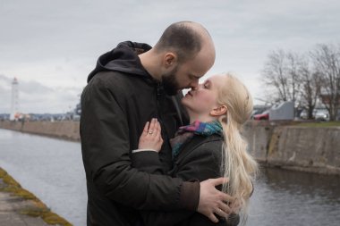 Uzun sarı saçlı güzel bir kadın ve deniz kenarında öpüşen bir çift.