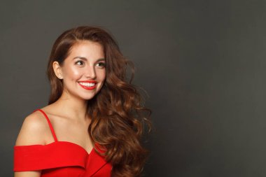 Parlak ciltli, dalgalı saç stili ve siyah arka planda kırmızı dudaklı neşeli manken kadın. 