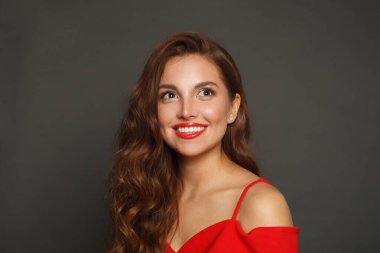 Çekici esmer kadın, modaya uygun makyajlı, kahverengi kıvırcık saçlı, siyah arka planda kırmızı dudaklı. 