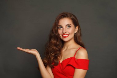 Esmer model kadın boş avuç içini tutuyor ve siyah arka plana bakıyor. 