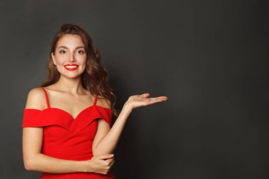 Başarılı model kadın avuç içi boşluğu tutuyor ve siyah arka plandaki kameraya bakıyor. 