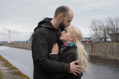 Sevgi dolu erkek ve kadın. Birbirlerine sarılıyorlar. Deniz kenarında öpüşüyorlar.