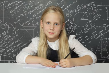 Okulun karatahta arka planında sınıfta oturan sevimli çocuk öğrenci. Matematik eğitimi kavramı