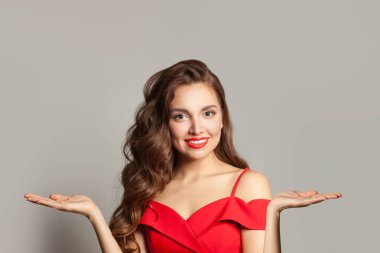 Güzel bir kadın iki boş avuç içini tutuyor ve beyaz arka planda kameraya bakıyor. 