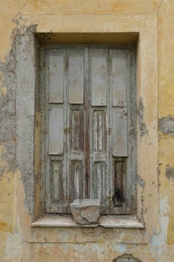Eski pencere, ahşap kepenkli ve yıpranmış terk edilmiş bir evin duvarı..