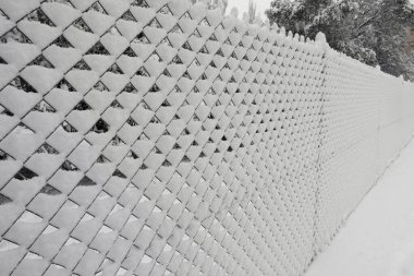 Soğuk kış gününde karla kaplı zincirli tel örgüler..