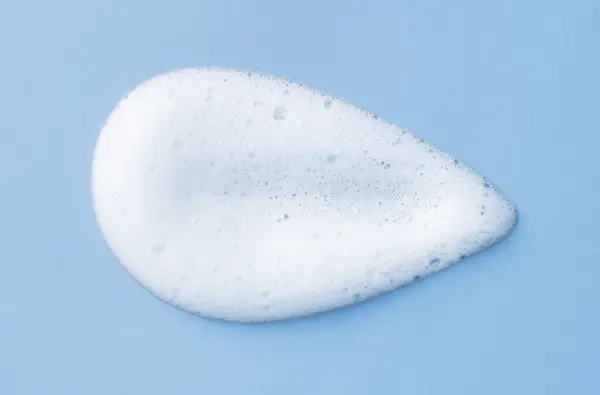 Açık Mavi Arka Planda Beyaz Cilt Köpüğü Temizliyor Sabun Şampuan — Stok fotoğraf