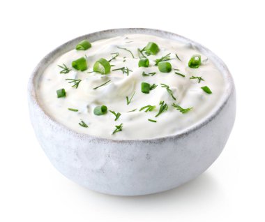 Beyaz seramik bir kase taze ekşi krema sosu ve beyaz arka planda yalıtılmış otlar.