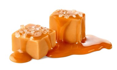 Karamel soslu ve beyaz zemin üzerinde izole edilmiş iki tuzlu karamel küp şeker.