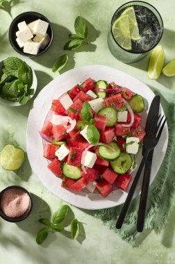 Bir tabak taze karpuz, salatalık ve fesleğen ve naneli feta salatası. Sağlıklı yaz yemekleri. Güneşli bir ışık. Üst görünüm