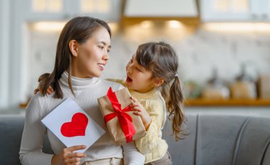 Anneler Günün kutlu olsun. Çocuk kızı annesini tebrik ediyor ve ona kartpostal ve hediye veriyor..