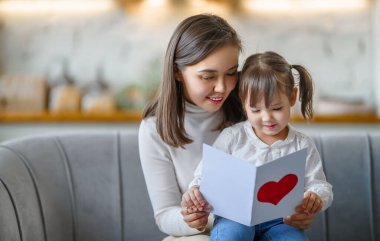 Anneler Günün kutlu olsun. Çocuk kızı annesini tebrik ediyor ve ona kartpostal veriyor..