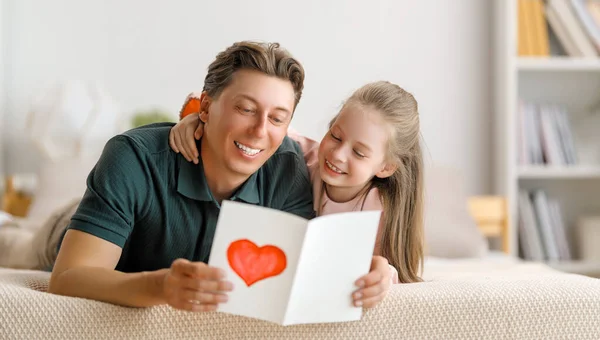 孩子的女儿在祝贺她的父亲 并给他寄明信片 爸爸和女孩都在笑着和拥抱 家庭假日和团聚 — 图库照片