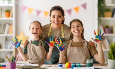 Sanat sınıfındaki mutlu çocuklar ve öğretmenler. Kadın ve çocuklar birlikte resim yapıyorlar..