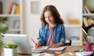 Okula dönelim. Mutlu çocuk masada oturuyor. Ödev yapan ya da online eğitim alan kız.