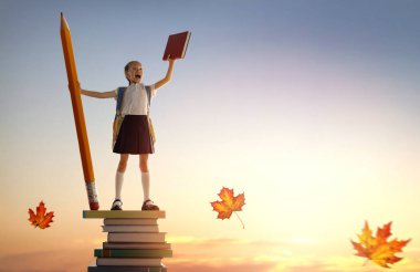 Okula dönün! Kitap kulesinde duran ve elinde günbatımı gökyüzünün arka planında kocaman bir kalem tutan mutlu, sevimli, çalışkan çocuk. Eğitim ve okuma kavramı. Hayal gücünün gelişimi..
