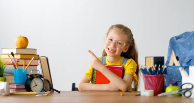 Okula dönün! Mutlu, sevimli, çalışkan çocuk kapalı bir masada oturuyor. Çocuk derste ya da derste öğreniyor.