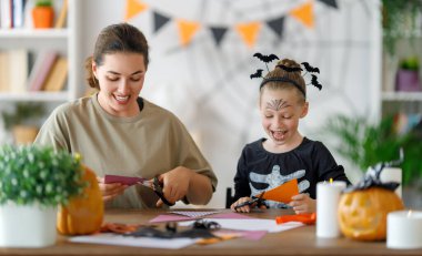 Mutlu Cadılar Bayramı, anne ve kızı balkabağı oyuyor. Aile tatili için hazırlanıyor.