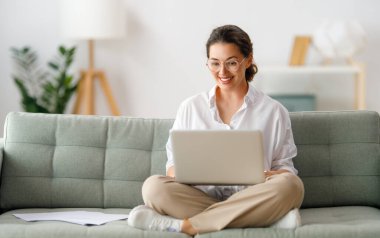 İnternette ders çalışan mutlu bir kadın, web sitesi izleyen, dizüstü bilgisayarda podcast yapan, notlar alan. E-öğrenme kavramı.