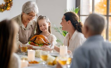 Şükran Günü, Sonbahar ziyafeti. Masada oturup bayramı kutlayan mutlu bir aile. Büyükanne ve büyükbaba, anne ve çocuklar. Geleneksel yemek..