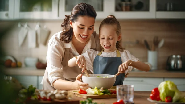 Healthy food at home. Happy family in the kitchen. Mother and child daughter are preparing proper meal.