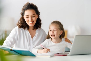 Okula dönelim. Mutlu çocuk ve yetişkin masada oturuyor. Ödev yapan ya da online eğitim alan kız.
