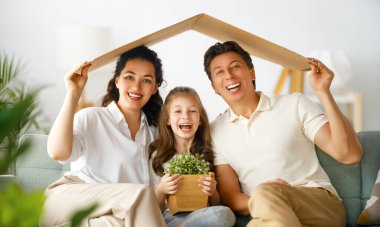 Anne, baba ve çocuk çatı sembolü olan odada. Genç aile için konut kavramı. 