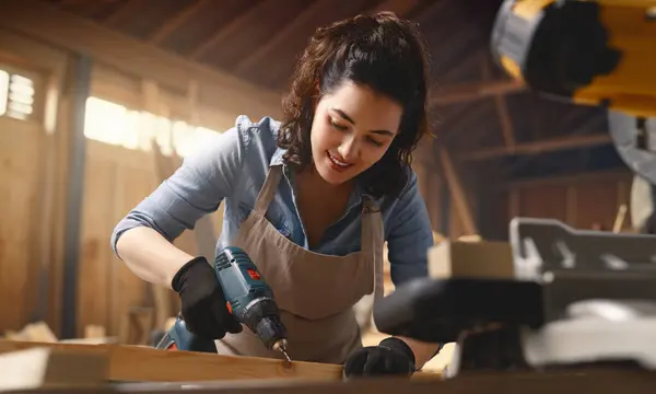 Young woman carpenter is working in a workshop.