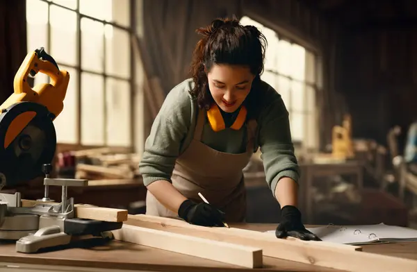 Young woman carpenter is working in a workshop.