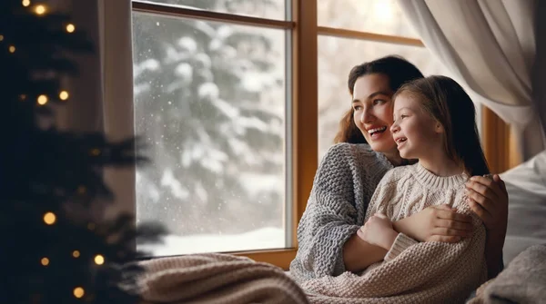 快乐温馨的家庭 母亲和女儿在窗前拥抱和享受冬天的自然 — 图库照片