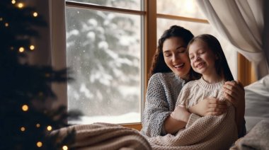 Sevgi dolu bir aile. Anne ve kız kucaklaşıyorlar ve kışın tadını çıkarıyorlar..