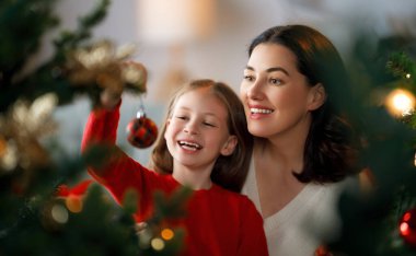 Mutlu Noeller, mutlu tatiller. Anne ve kızı kapalı alanda ağacın yanında. Noel 'den önceki sabah. 