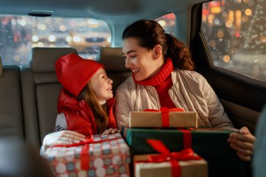 Kadın ve çocuğu ellerinde hediyelerle eve götürüyorlar. Tatil konsepti. Noel arifesi. 
