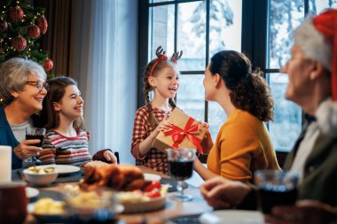  Mutlu Noeller! Mutlu aile evde yemek yiyor. Kutlama tatili ve ağacın yakınındaki birliktelik.