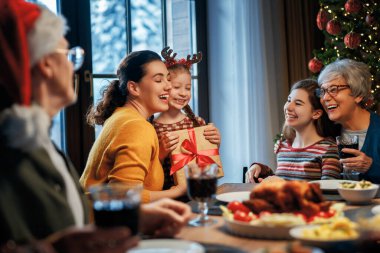  Mutlu Noeller! Mutlu aile evde yemek yiyor. Kutlama tatili ve ağacın yakınındaki birliktelik.