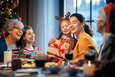  Mutlu Noeller! Mutlu aile evde yemek yiyor. Kutlama tatili ve ağacın yakınındaki birliktelik.