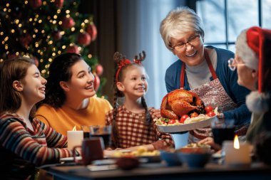 Mutlu Noeller! Mutlu aile evde yemek yiyor. Kutlama tatili ve ağacın yakınındaki birliktelik.