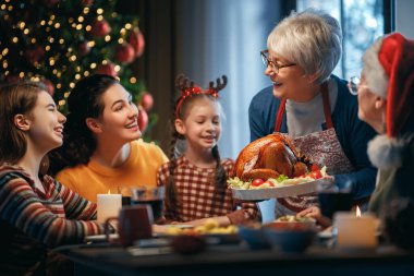 Mutlu Noeller! Mutlu aile evde yemek yiyor. Kutlama tatili ve ağacın yakınındaki birliktelik.