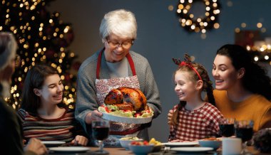 Mutlu Noeller! Mutlu aile evde yemek yiyor. Kutlama tatili ve ağacın yakınındaki birliktelik.