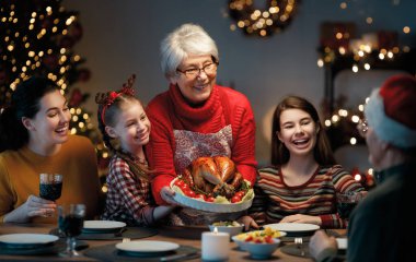 Mutlu Noeller! Mutlu aile evde yemek yiyor. Kutlama tatili ve ağacın yakınındaki birliktelik.