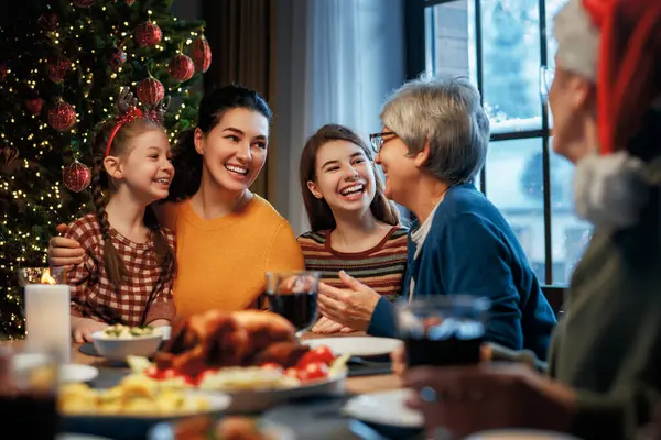 Mutlu Noeller! Mutlu aile evde yemek yiyor. Kutlama tatili ve ağacın yakınındaki birliktelik.