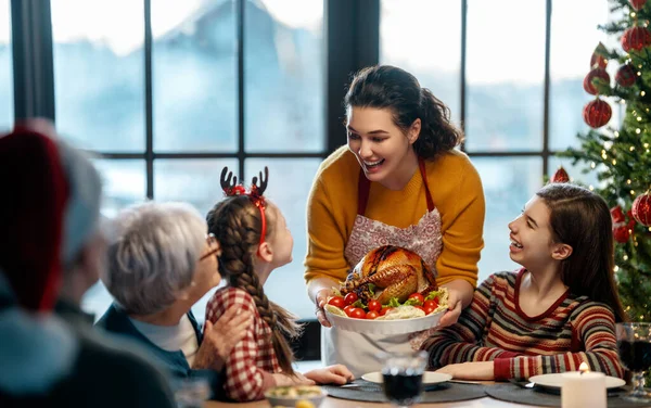 Mutlu Noeller! Mutlu aile evde yemek yiyor. Kutlama tatili ve ağacın yakınındaki birliktelik.