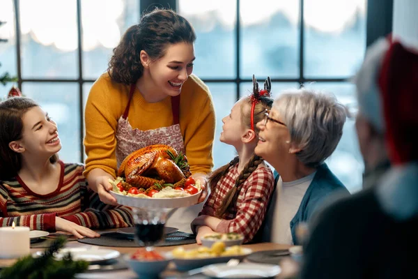Mutlu Noeller! Mutlu aile evde yemek yiyor. Kutlama tatili ve ağacın yakınındaki birliktelik.