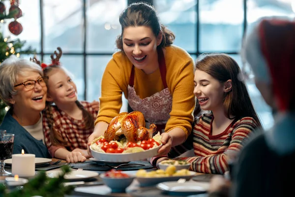 Mutlu Noeller! Mutlu aile evde yemek yiyor. Kutlama tatili ve ağacın yakınındaki birliktelik.