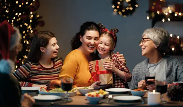  Mutlu Noeller! Mutlu aile evde yemek yiyor. Kutlama tatili ve ağacın yakınındaki birliktelik.