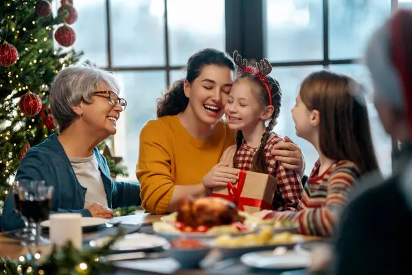 Mutlu Noeller! Mutlu aile evde yemek yiyor. Kutlama tatili ve ağacın yakınındaki birliktelik.