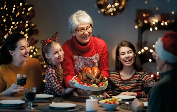 Mutlu Noeller! Mutlu aile evde yemek yiyor. Kutlama tatili ve ağacın yakınındaki birliktelik.