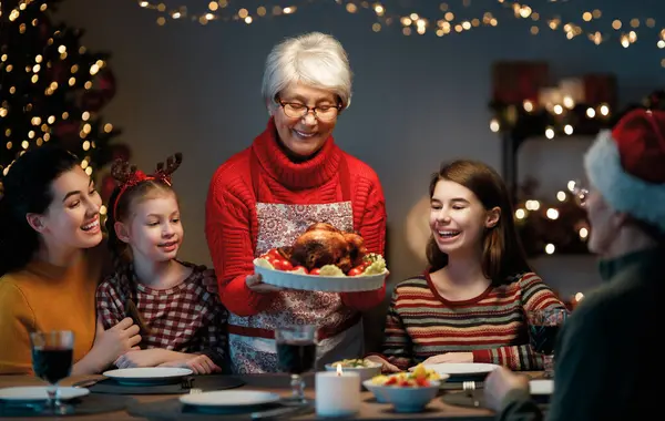 Mutlu Noeller! Mutlu aile evde yemek yiyor. Kutlama tatili ve ağacın yakınındaki birliktelik.